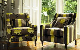 two black and green fabric armchairs with throw pillows near glass wall